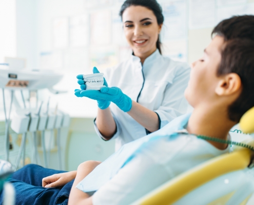 Female dentist shows dentures to little boy